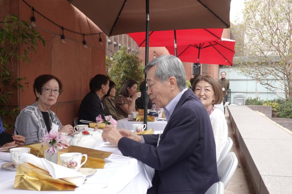 men and woman sitting at table have tea at event
